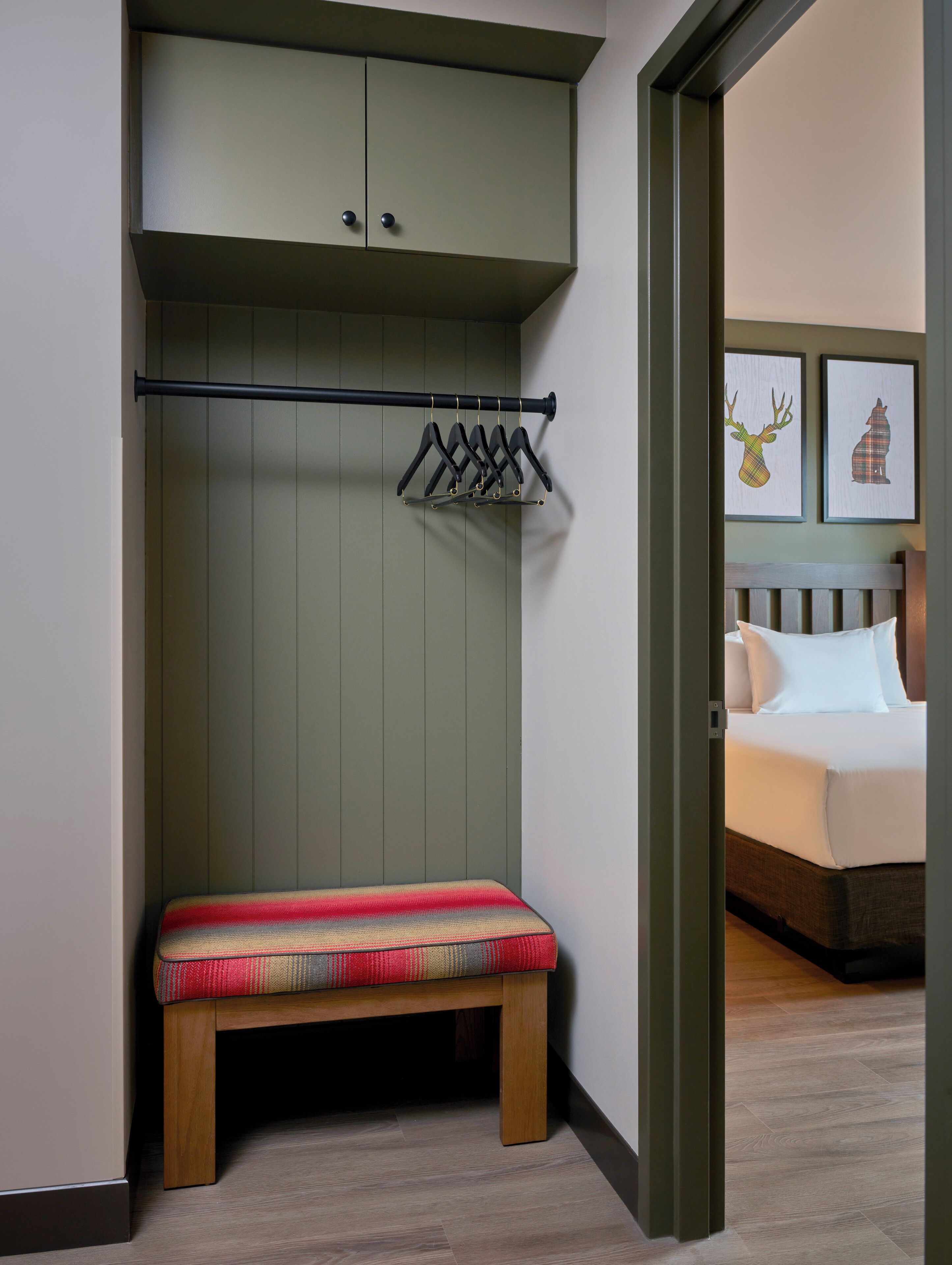 A room with a bench, a wardrobe, and a bed.