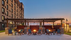 An outdoor patio with a fire pit, seating area, and a pergola. - Great Wolf Lodge Webster (Webster)