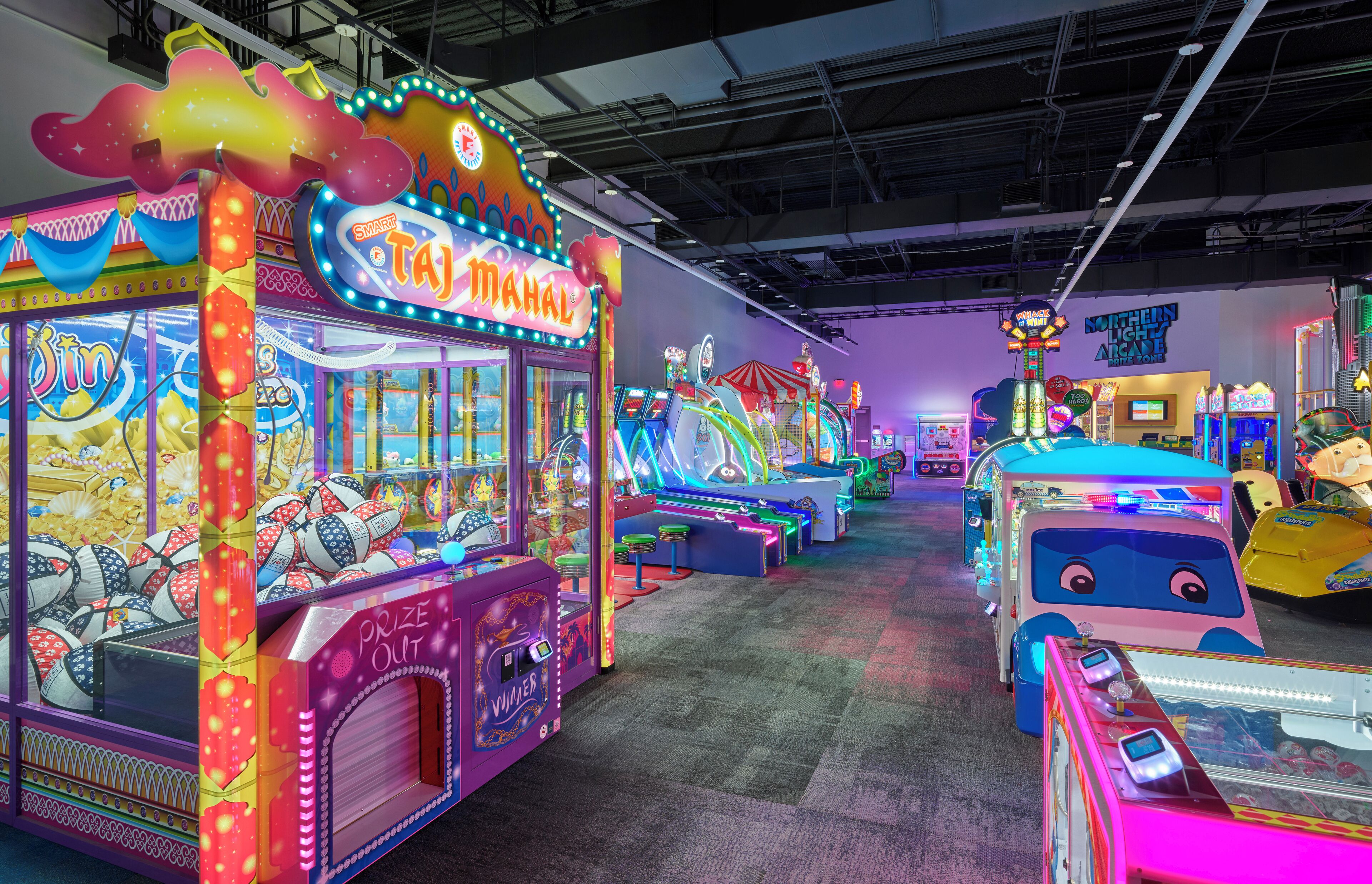 Una sala giochi al chiuso con luminose macchine da gioco e un cartello con scritto "MAHAL".