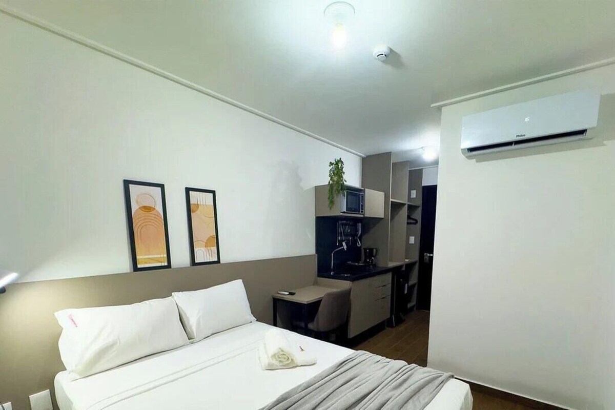 Habitación de hotel con cama, escritorio, microondas y aire acondicionado.