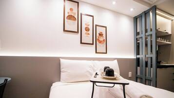 Una habitación de hotel con cama, una mesita con cafetera y obras de arte en la pared.
