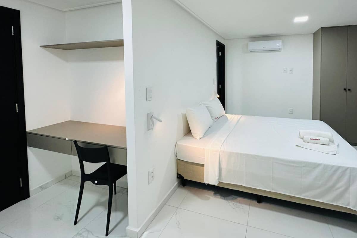 A small, modern bedroom with a bed, a desk, and a chair.