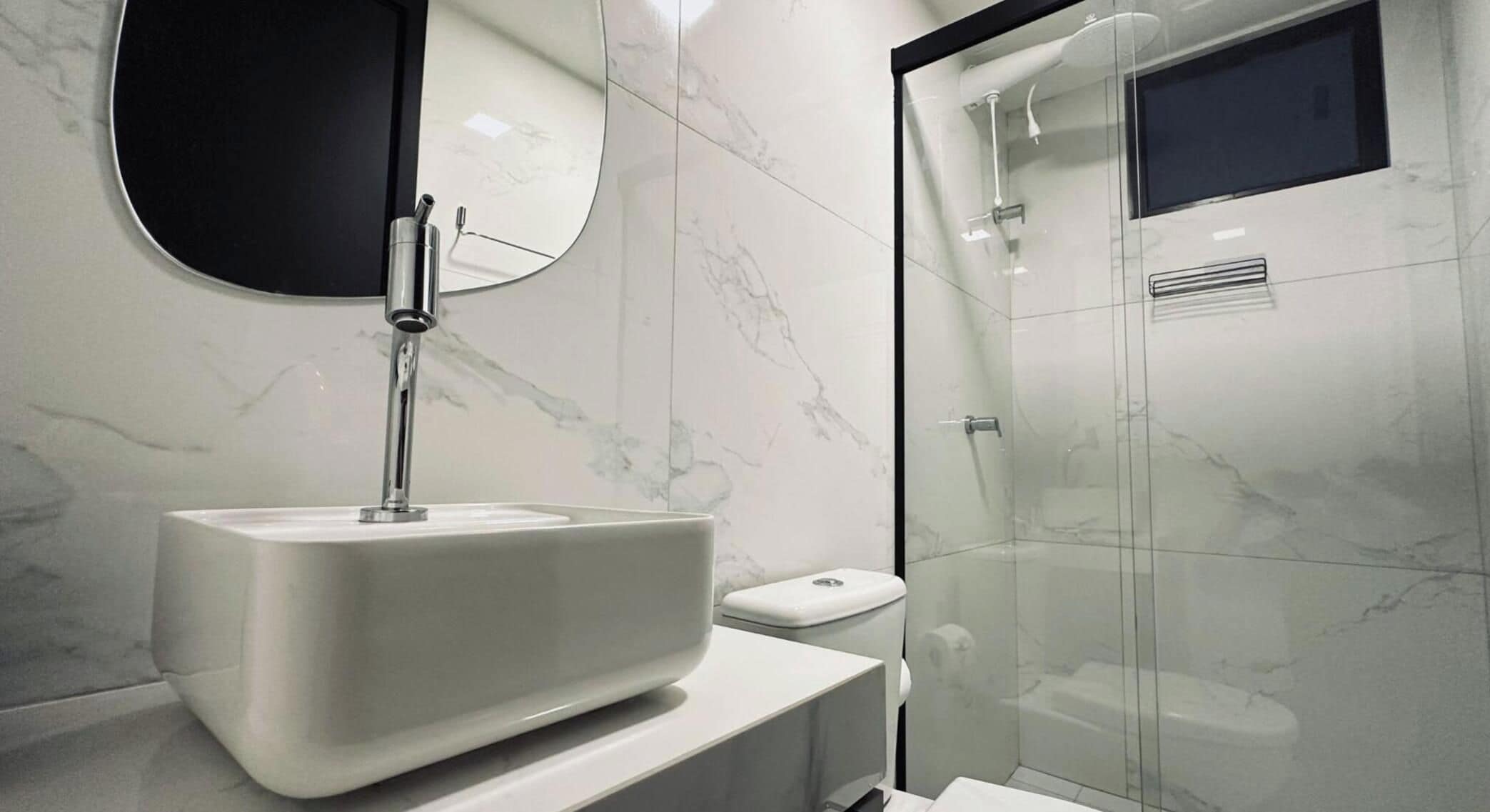 A modern bathroom with a marble sink, a glass shower enclosure, and a toilet.