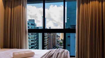 Une chambre d’hôtel avec une grande fenêtre, un lit et des rideaux.
