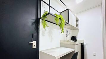 A modern bathroom with a black door, a white sink, a mirror, and a plant.