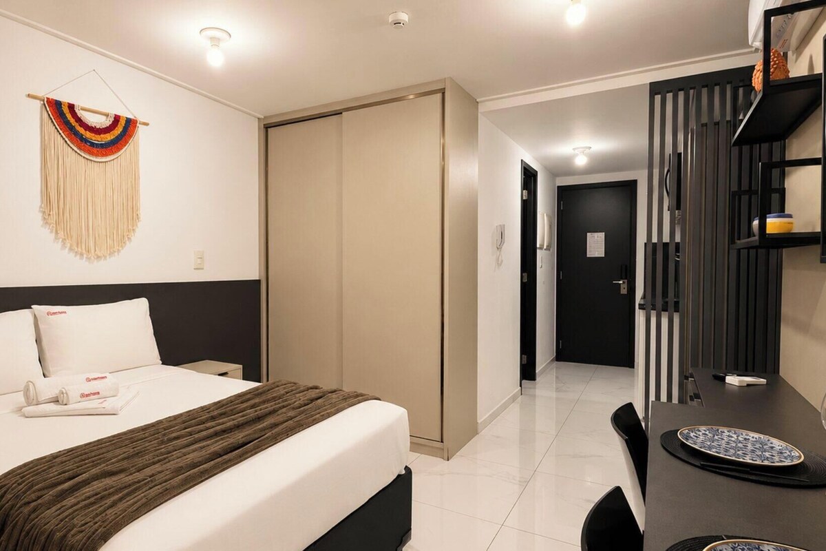 Habitación de hotel con cama, escritorio, silla, armario y un adorno en la pared.
