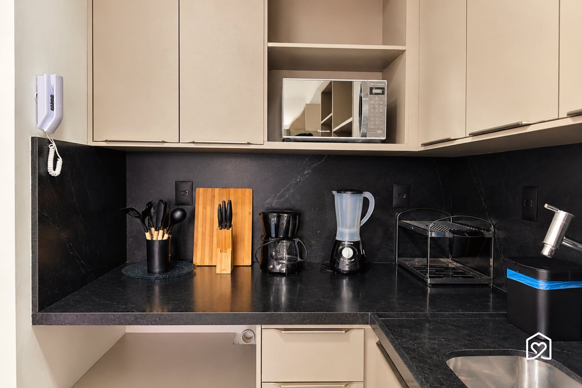 Een keuken met een magnetron, koffiezetapparaat, blender en een messenblok.