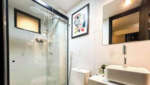 A modern bathroom with a glass-enclosed shower, a white toilet, and a sink with a mirror above. - Move Tambaú II - LikeHome Hospedagens (João Pessoa)