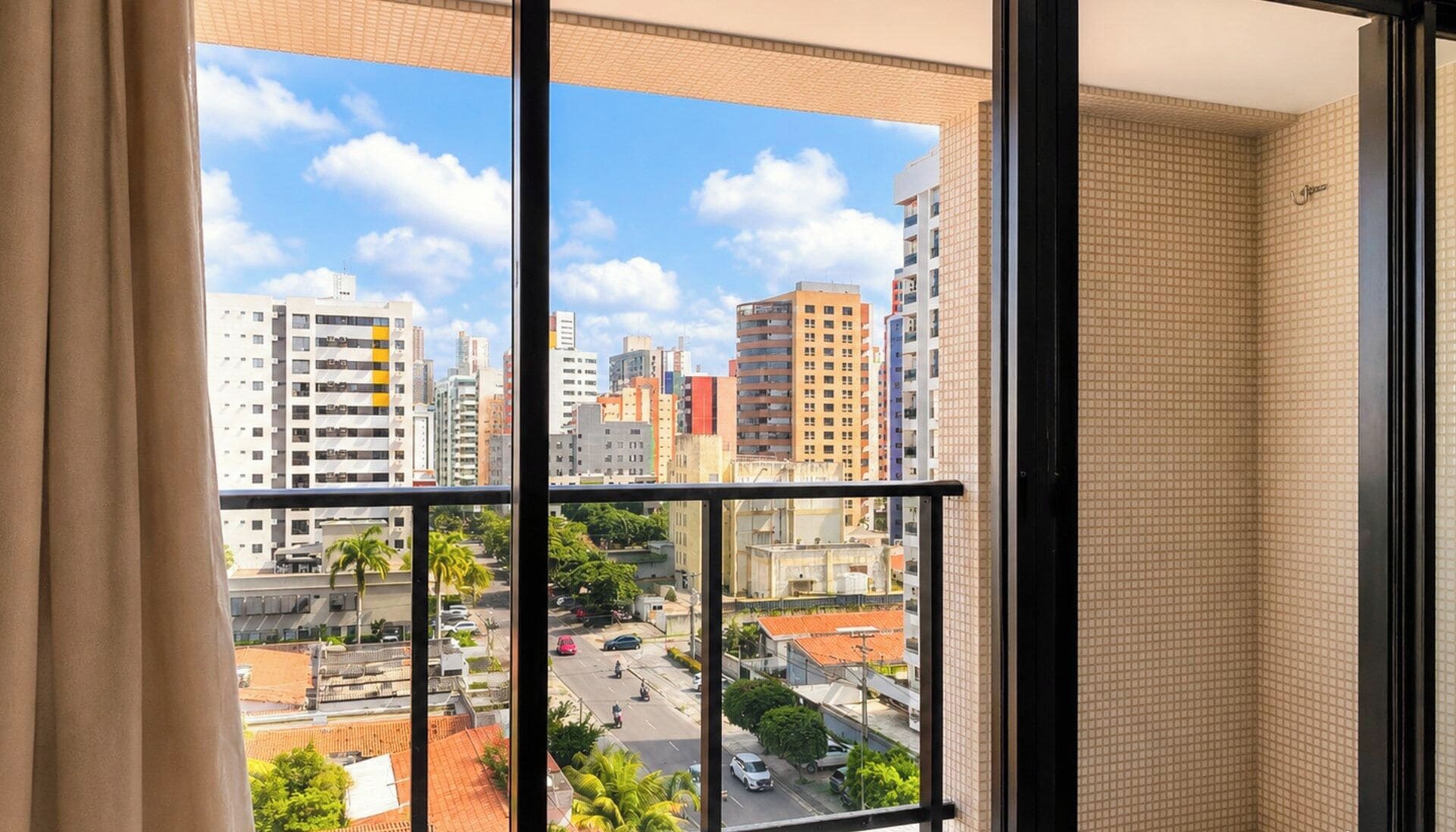 A high-rise building with multiple floors, large windows, and a view of a cityscape with various buildings and a street.