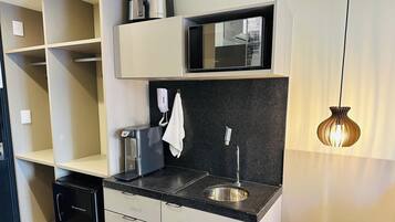 A modern kitchen with a built-in microwave, a coffee maker, a kettle, and a sink.
