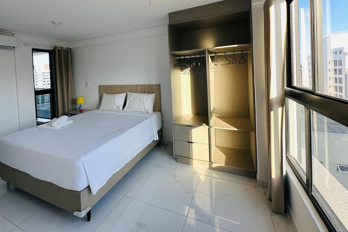 A hotel room with a bed, a wardrobe, and a window with a city view.
