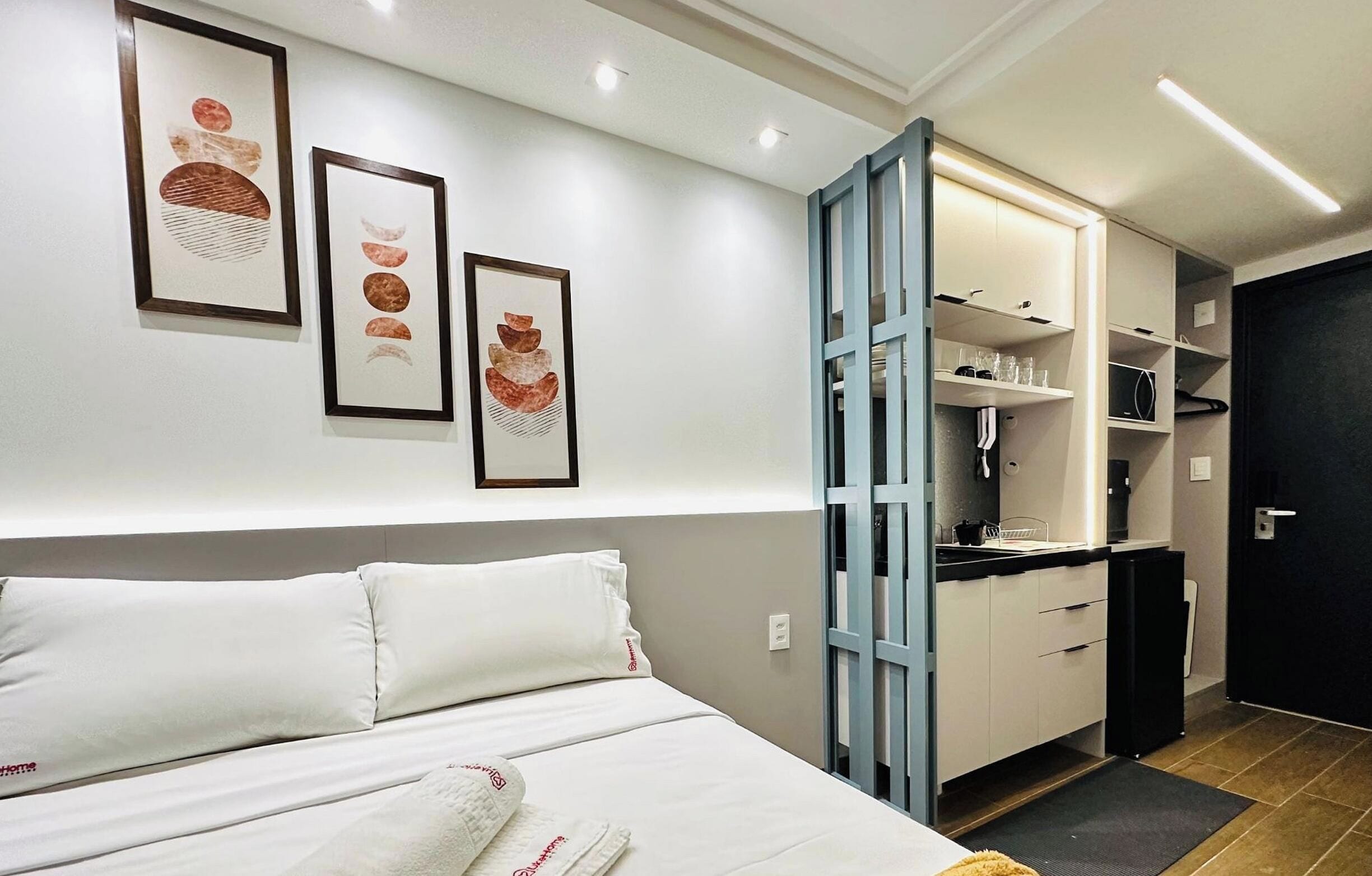 A hotel room with a bed, a wardrobe, and a kitchenette.