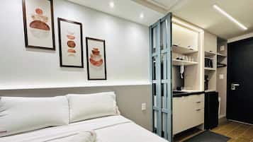A hotel room with a bed, a wardrobe, and a kitchenette.
