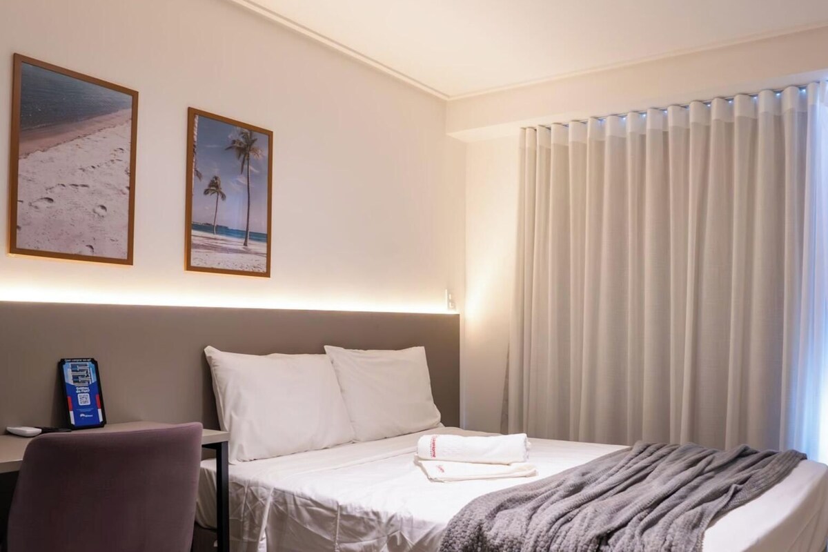 Una habitación de hotel con una cama, un escritorio y dos cuadros en la pared.