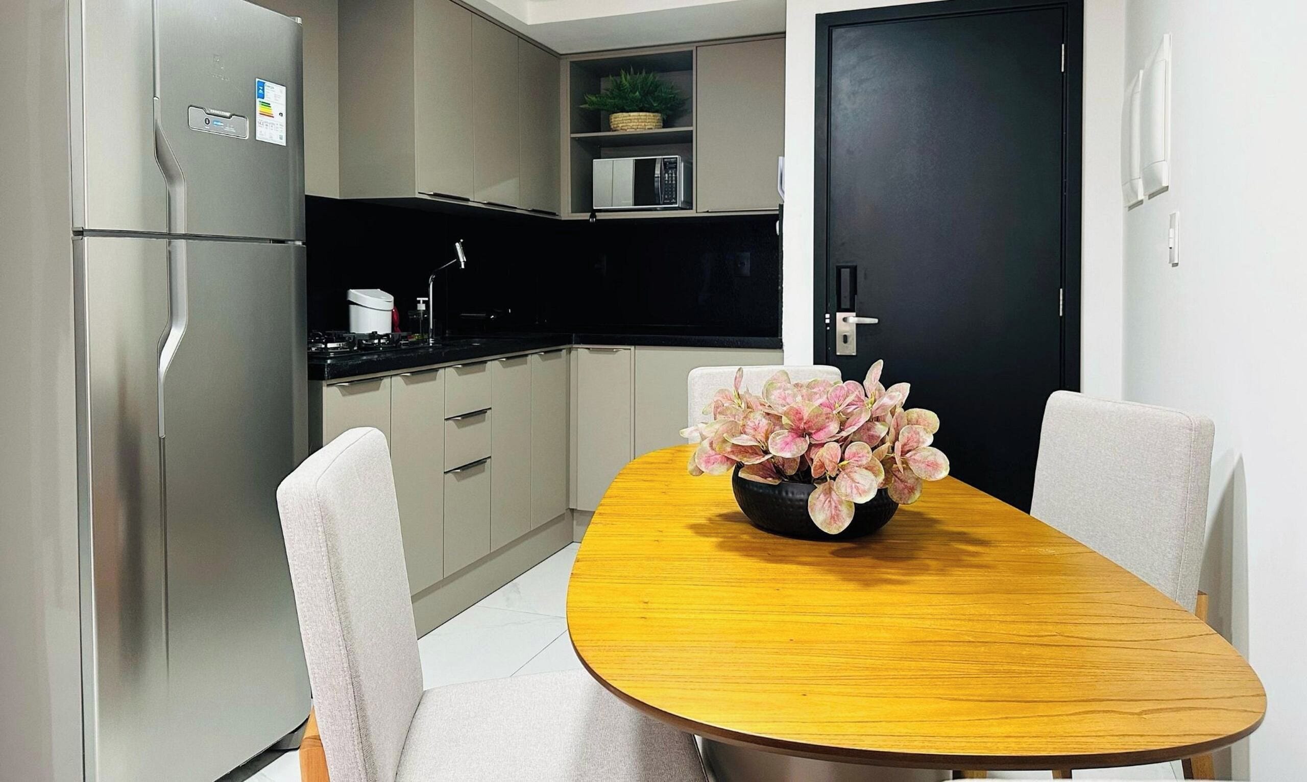 A modern kitchen with a dining table, chairs, and a refrigerator.