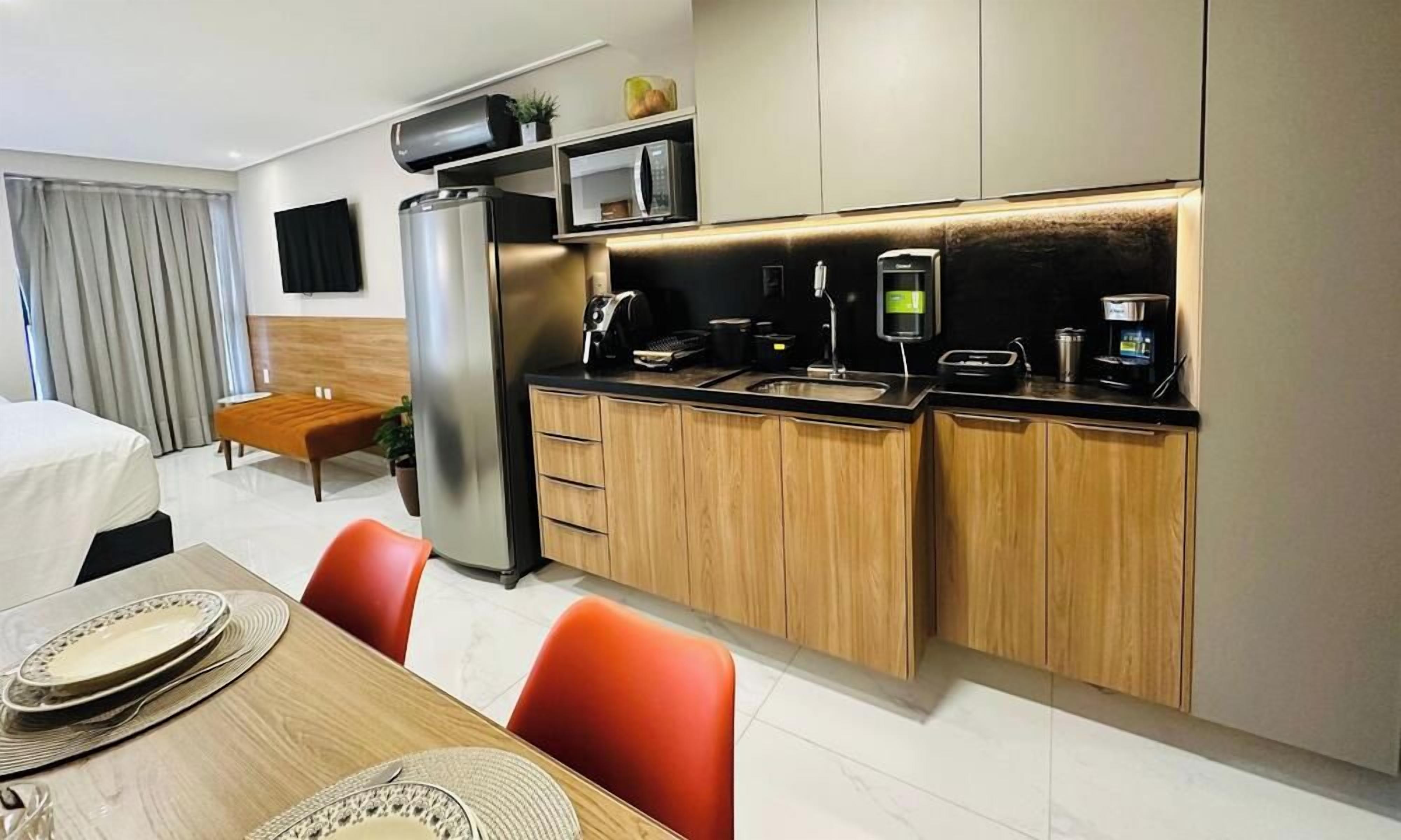 Een compacte hotelkamer met een kitchenette, een eethoek en een bed.