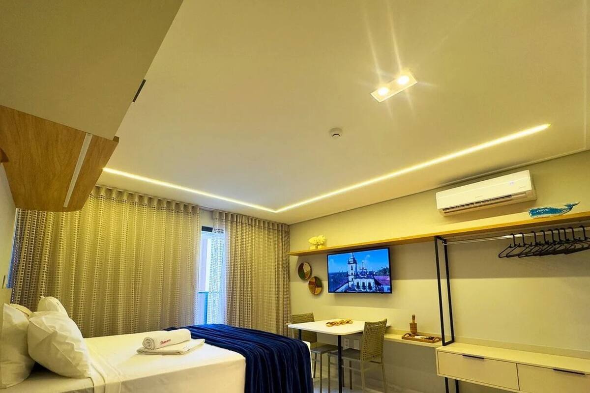 A modern hotel room with a bed, a desk, and a TV.