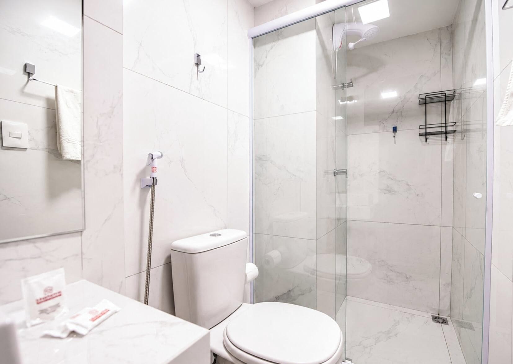 A modern bathroom with a glass-enclosed shower, a toilet, and a sink.