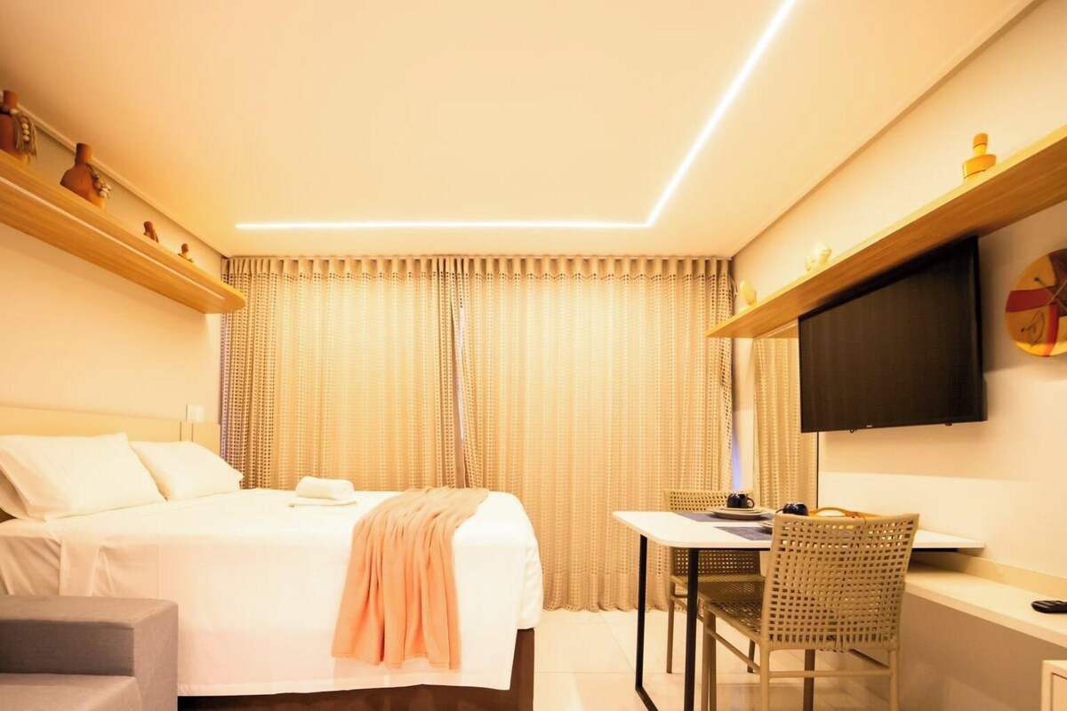Una habitación de hotel con una cama, un escritorio, una silla, un televisor y un estante con adornos.