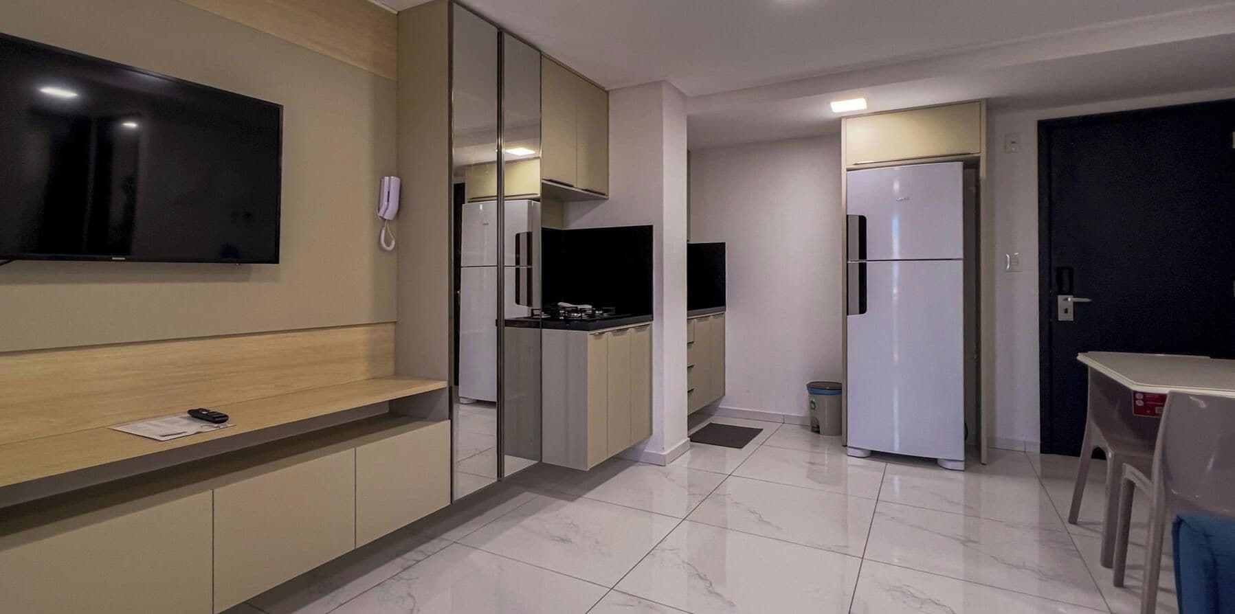 Eine moderne Küche mit integriertem Fernseher, einem Kühlschrank und einer kleinen Essecke.
