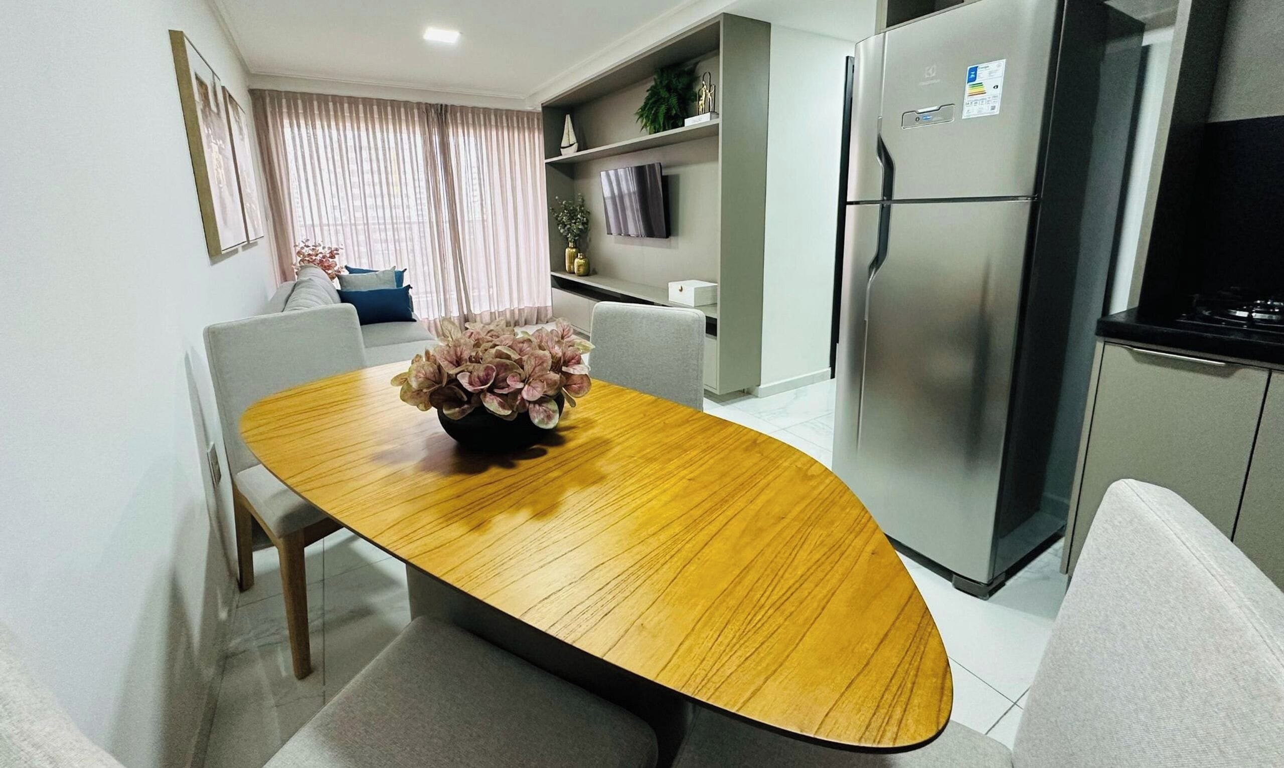 Una cocina moderna con refrigerador empotrado, una mesa de comedor con sillas y un jarrón decorativo.