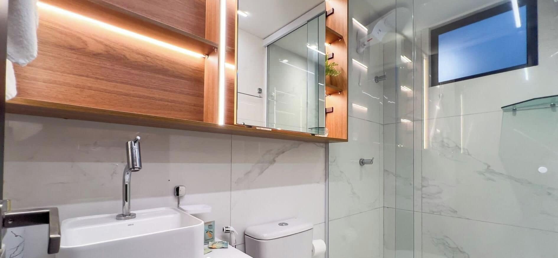 Une salle de bain moderne avec un lavabo blanc, un miroir et une cabine de douche en verre.