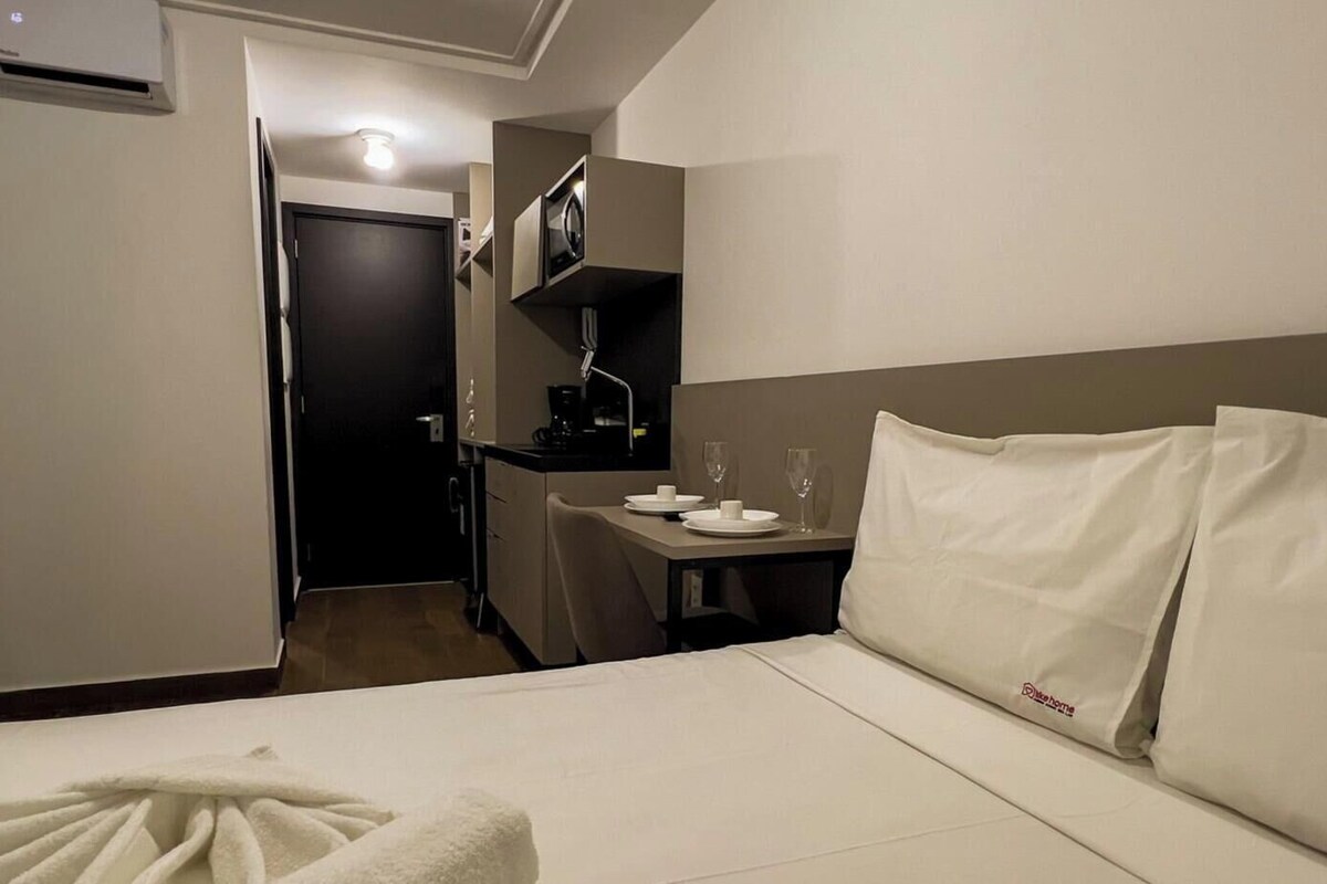 Una habitación de hotel con una cama, un escritorio, un microondas y una cafetera.
