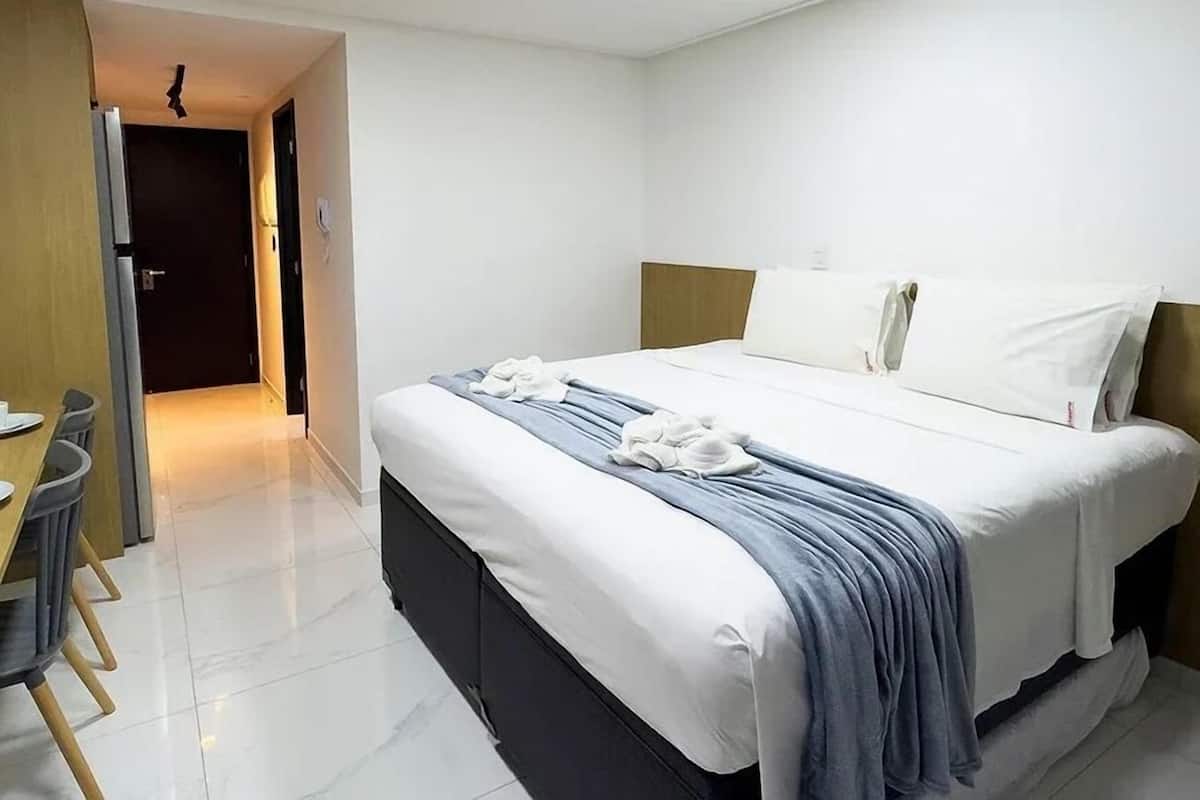 A hotel room with a bed, a desk, and a chair.