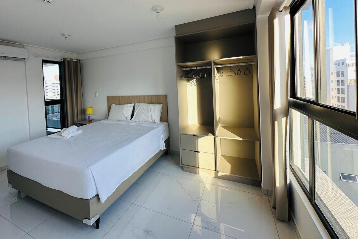 Una habitación de hotel con cama, armario y ventana con vista a la ciudad.