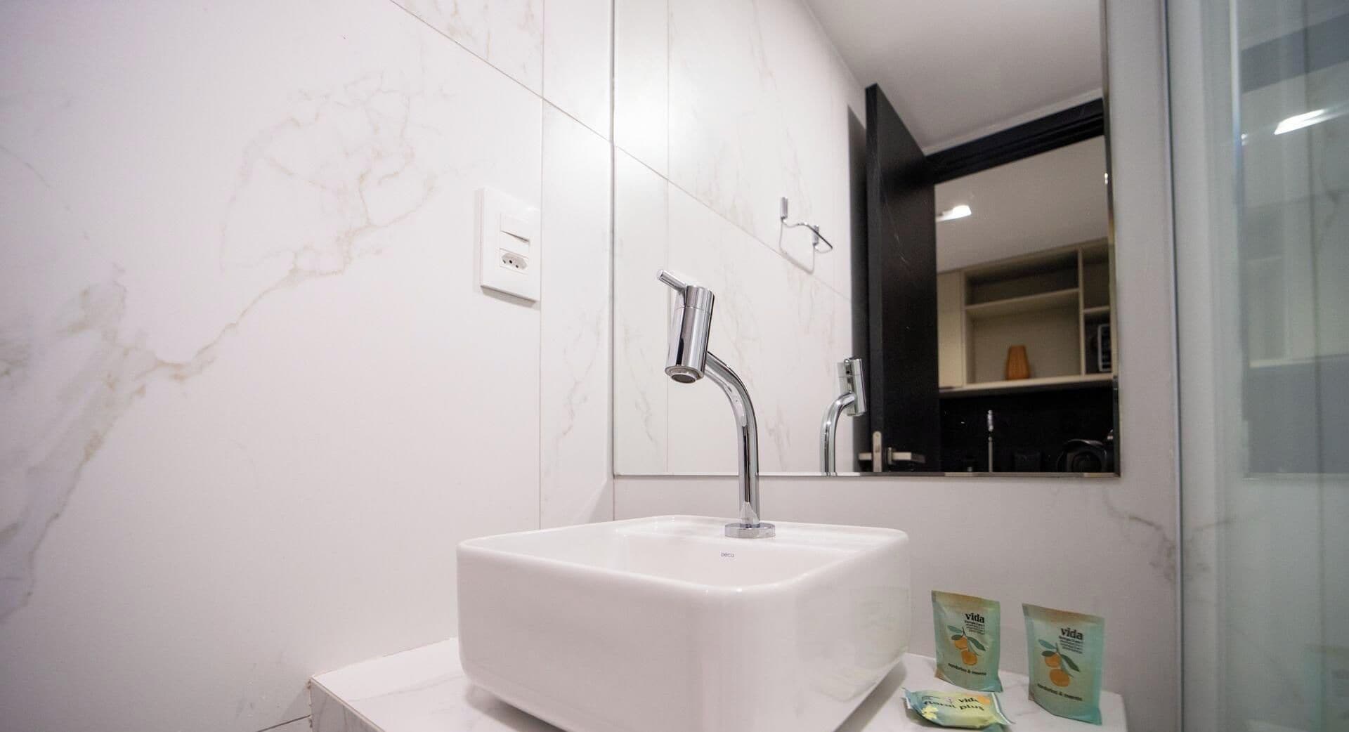 Une salle de bain moderne avec un lavabo blanc, un robinet chromé et un miroir au-dessus.