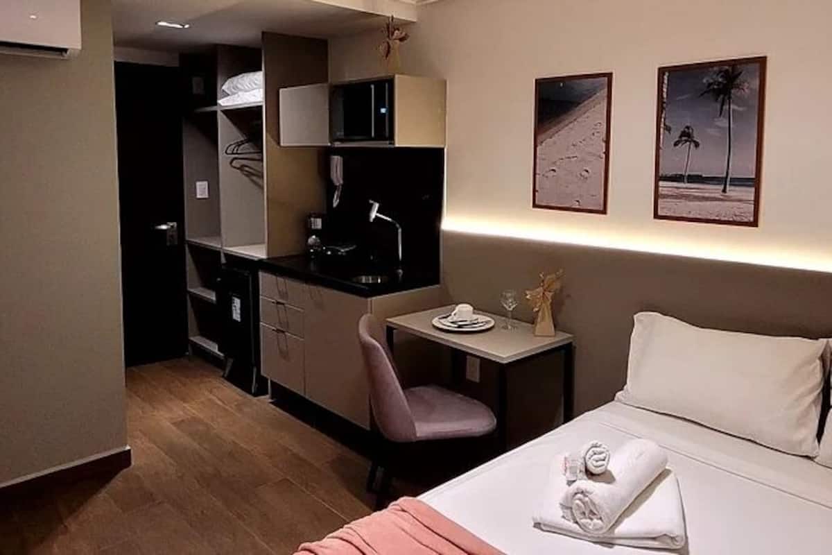 A hotel room with a bed, a desk, a chair, and a small table.