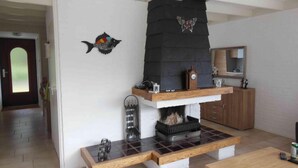 A living room with a fireplace, a wooden bench, and a mirror above a cabinet. - Holiday Villa in Sint Maartenszee (Sint Maartensvlotbrug)