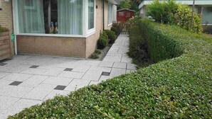 A modern two-story house with a flat roof, large windows, and a paved driveway. - Holiday Villa in Sint Maartenszee (Sint Maartensvlotbrug)