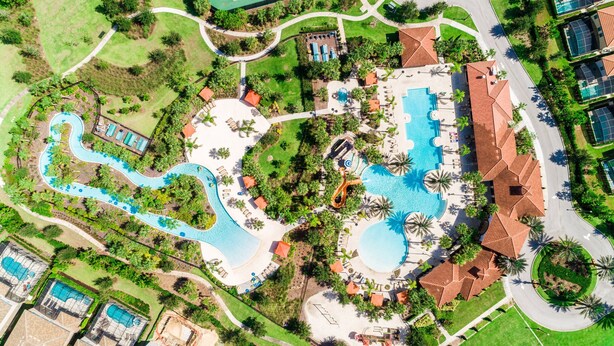 Vista aérea de un complejo turístico con varias piscinas, un tobogán de agua y una cancha de tenis.