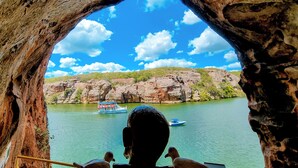 Uitzicht door een natuurlijke rotsboog, met een rivier en bootjes in de verte.