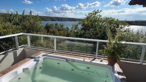 Een bubbelbad op een balkon met uitzicht op een meer en bomen.