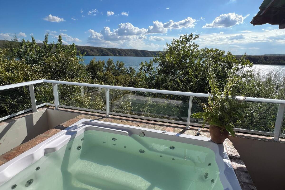 Boblebad på en balkon med udsigt over et sølandskab og træer.