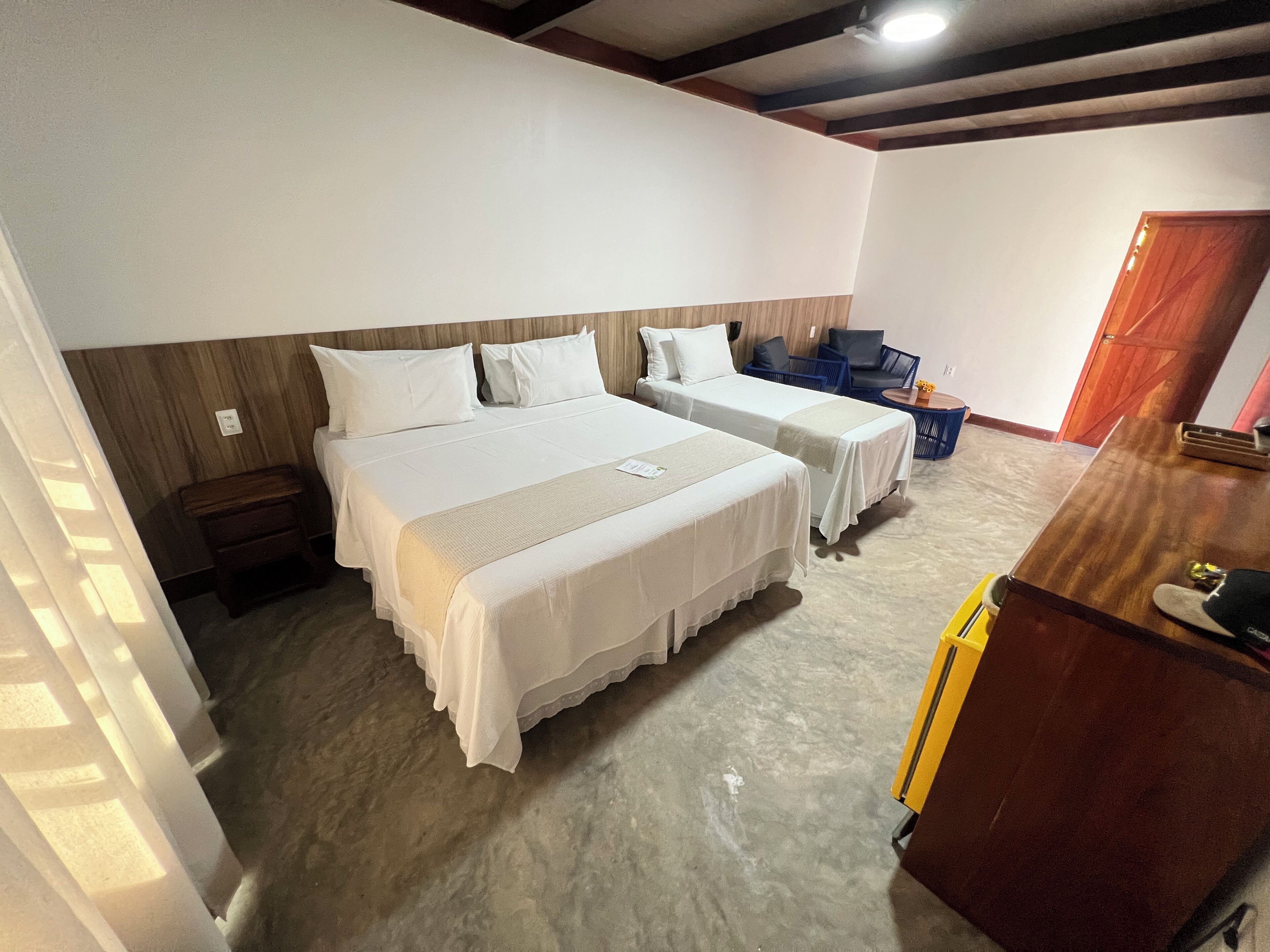 Ein Hotelzimmer mit zwei Betten, einem Holzkopfstück, einem kleinen Tisch und einer Tür.