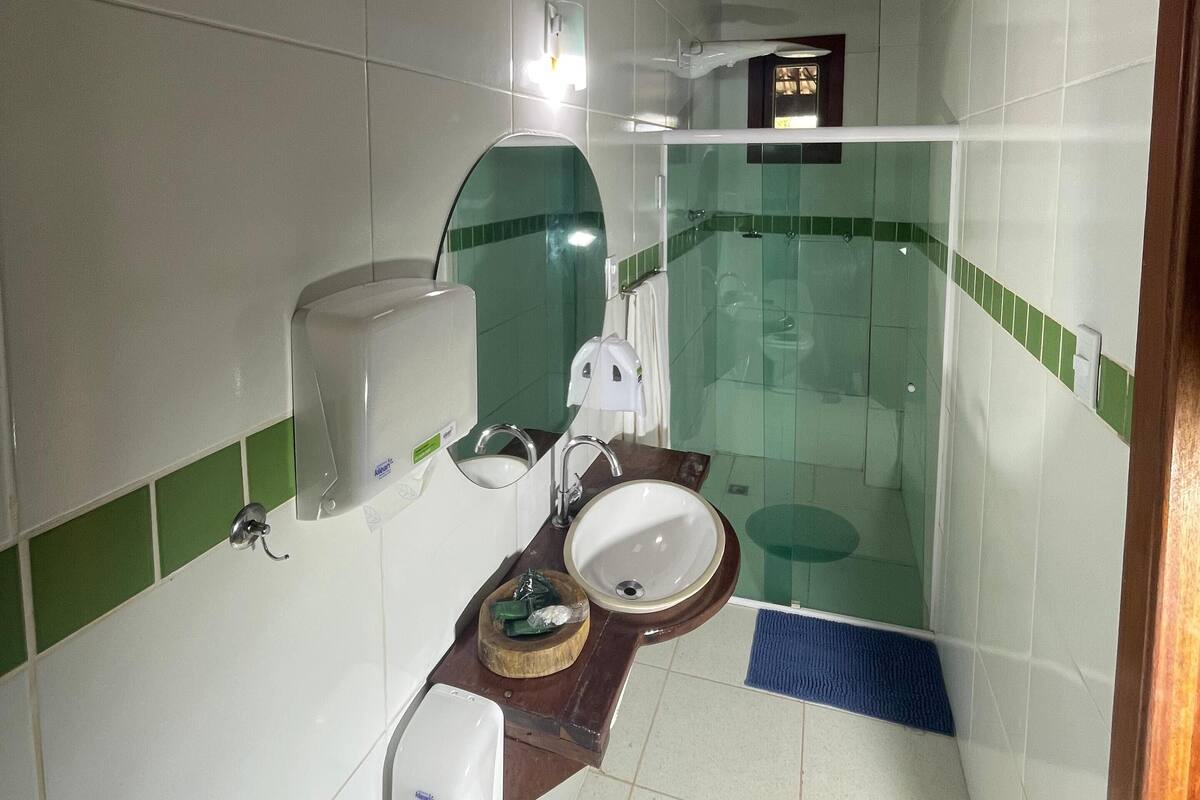 Et lille badeværelse med vask, spejl og toilet.