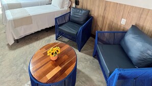 Een hotelkamer met twee bedden, een blauwe bank, een blauwe stoel en een houten salontafel met een bloevas.