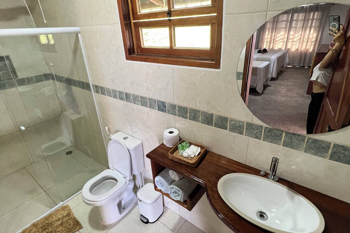 Et moderne badeværelse med bruser, toilet, vask og et lille vindue.