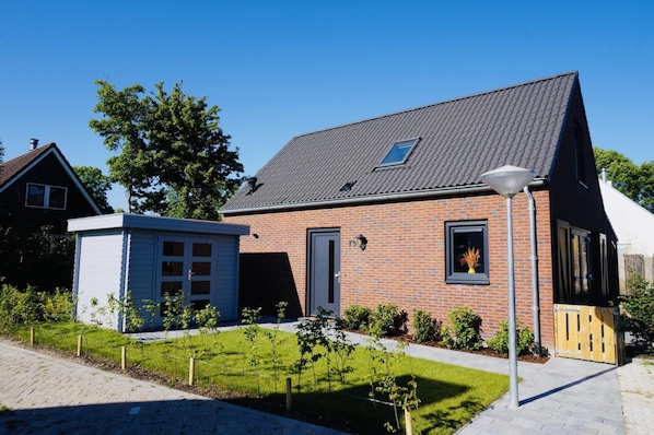 A two-story brick house with a sloped roof, a small attached garage, and a well-maintained lawn.