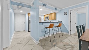 A modern kitchen with a microwave, wooden cabinets, and two bar stools.
