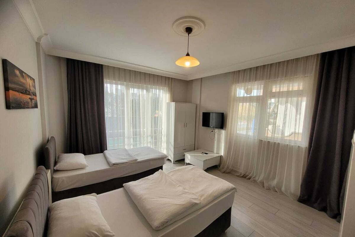 A hotel room with two beds, a TV, a wardrobe, and a painting on the wall.