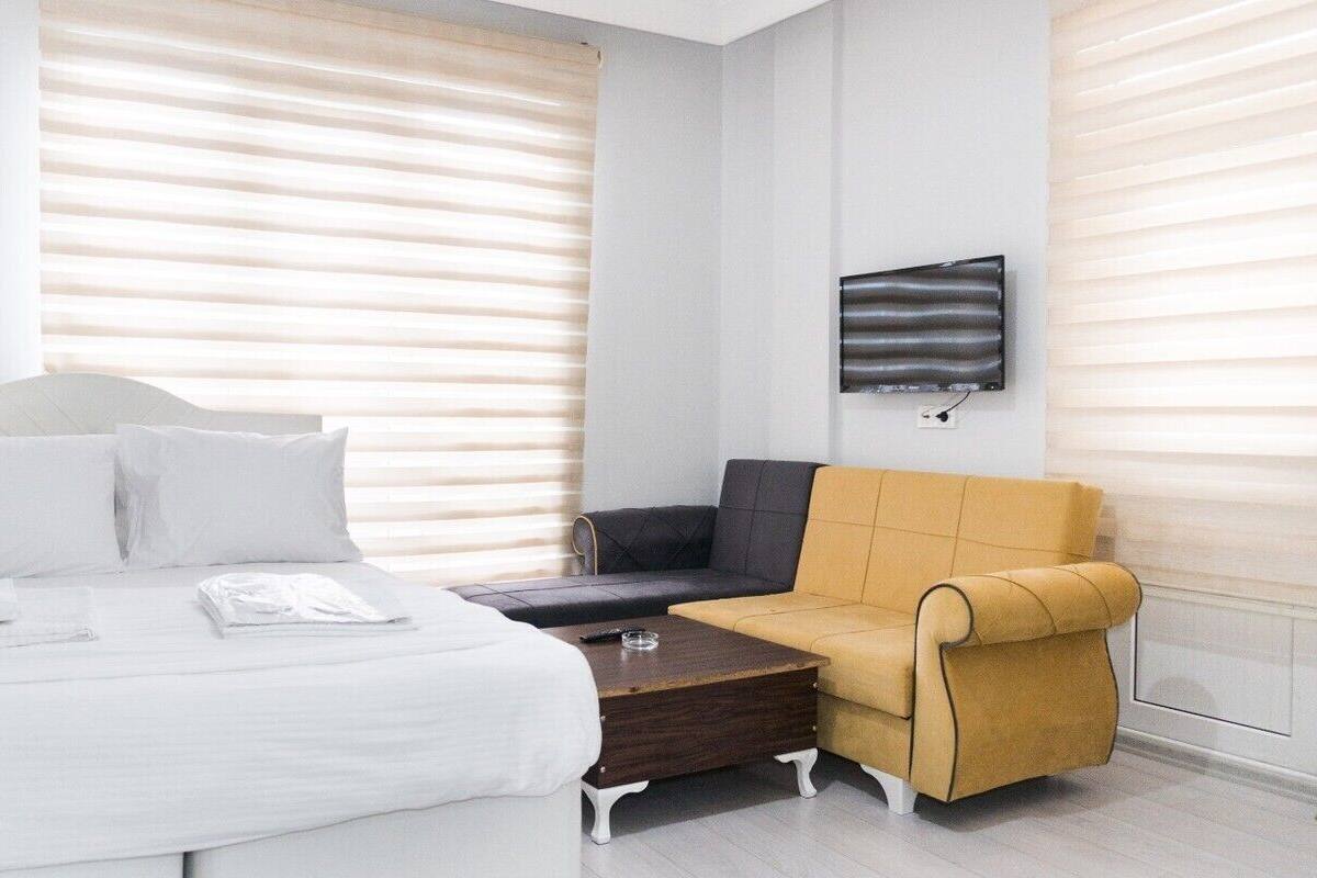 A hotel room with a bed, a sofa, a coffee table, and a TV mounted on the wall.