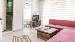 Una sala de estar moderna con un sofá, una mesa de centro y un televisor sobre un mueble de madera.