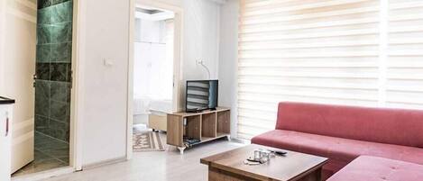 A modern living room with a sofa, coffee table, and a television on a wooden cabinet.
