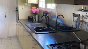A modern kitchen with a gas stove, double sink, and green cabinets. - Villa Soleil Located in a quiet, serene residential area (Vauclin)
