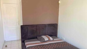 A bedroom with a bed, a door, and a light switch on the wall. - Villa Soleil Located in a quiet, serene residential area (Vauclin)