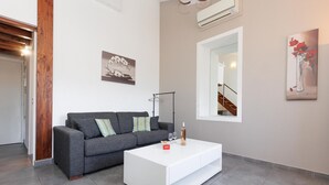 Ein modernes Wohnzimmer mit grauem Sofa, weißem Couchtisch und Kunstwerken an den Wänden.